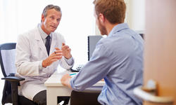 Male Patient Having Consultation With Doctor In Of